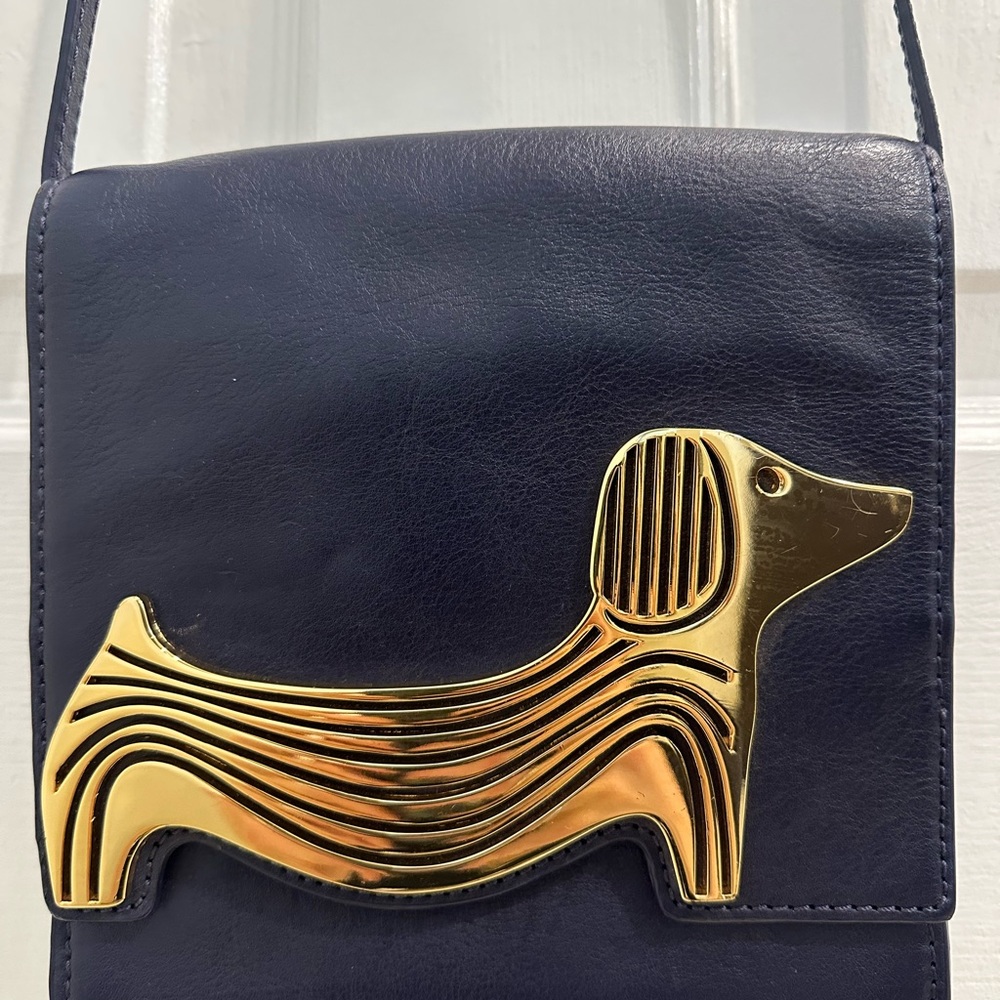 Adorable cross body purse with dog metal embellishment.